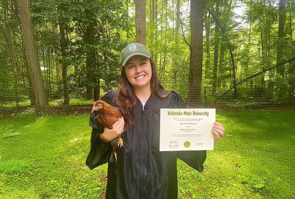 Tara Westington holding a chicken and her degree.