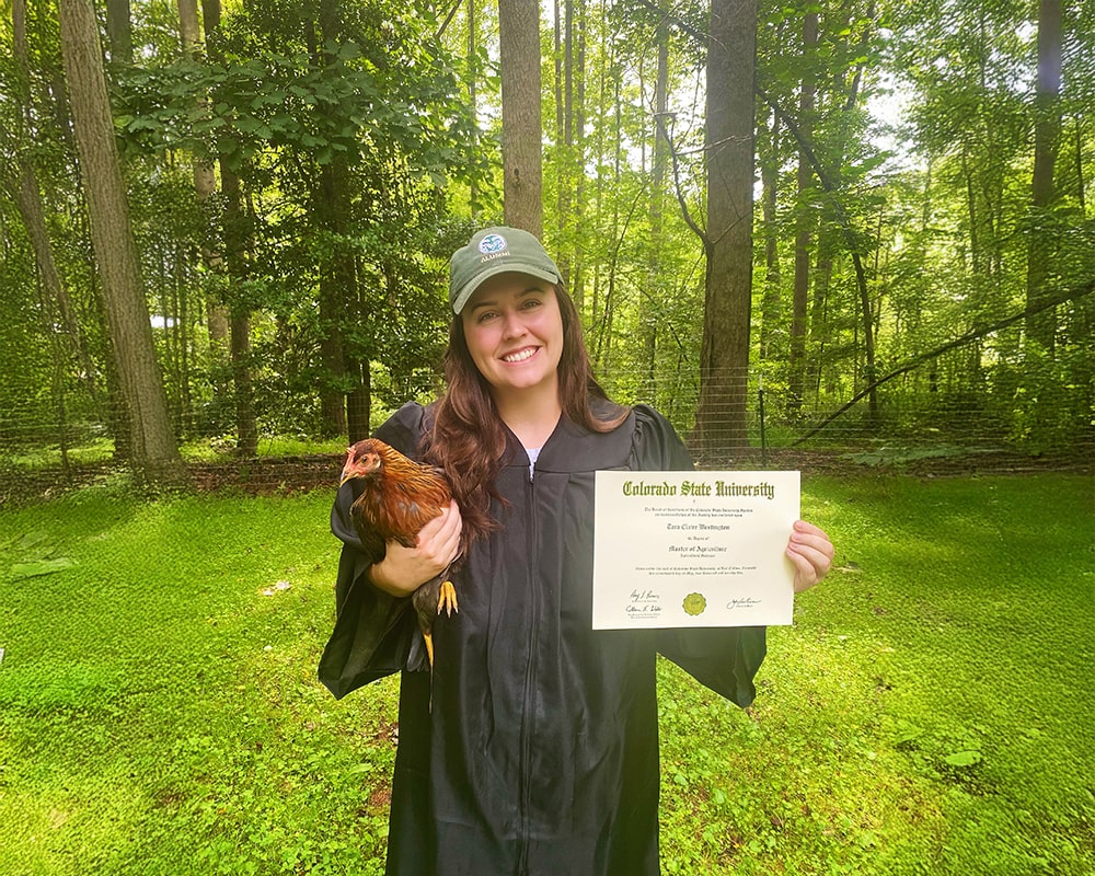 Tara Westington holding a chicken and her degree.