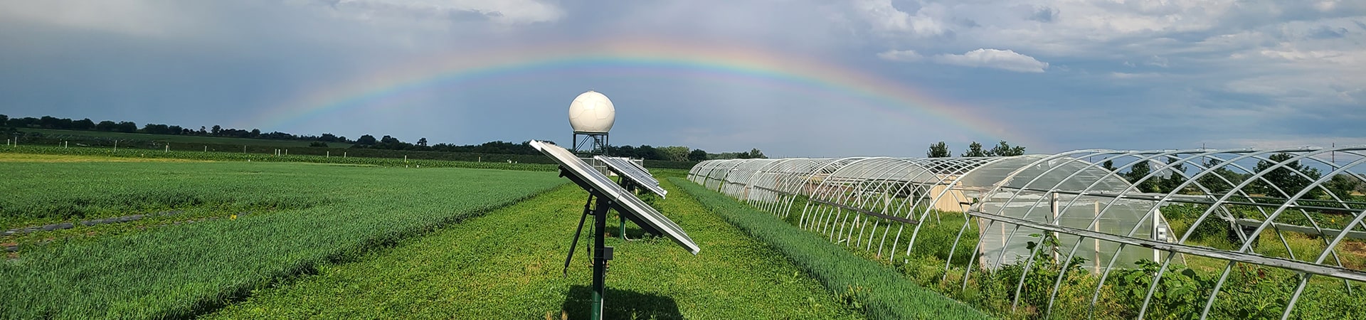 A solar panel next to greenhouses